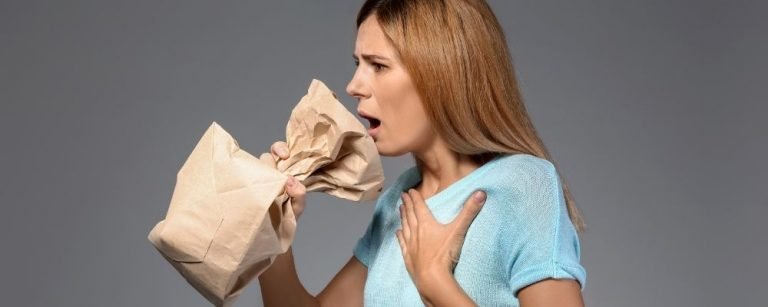 Vrouw met hyperventilatie ademt in een zak