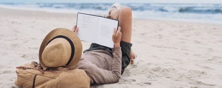 Man lies quietly on the beach reading a book