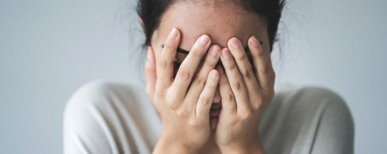 Woman feeling guilty with hands in front of her eyes