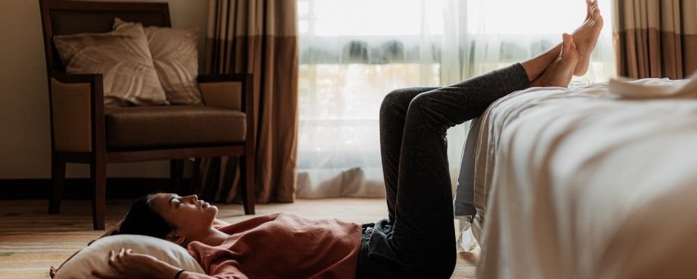 Vrouw met stress in benen terwijl ze haar benen omhoog houdt op het bed